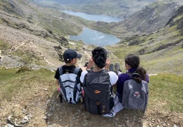 Three people seated on a cliff edge staring out. 
