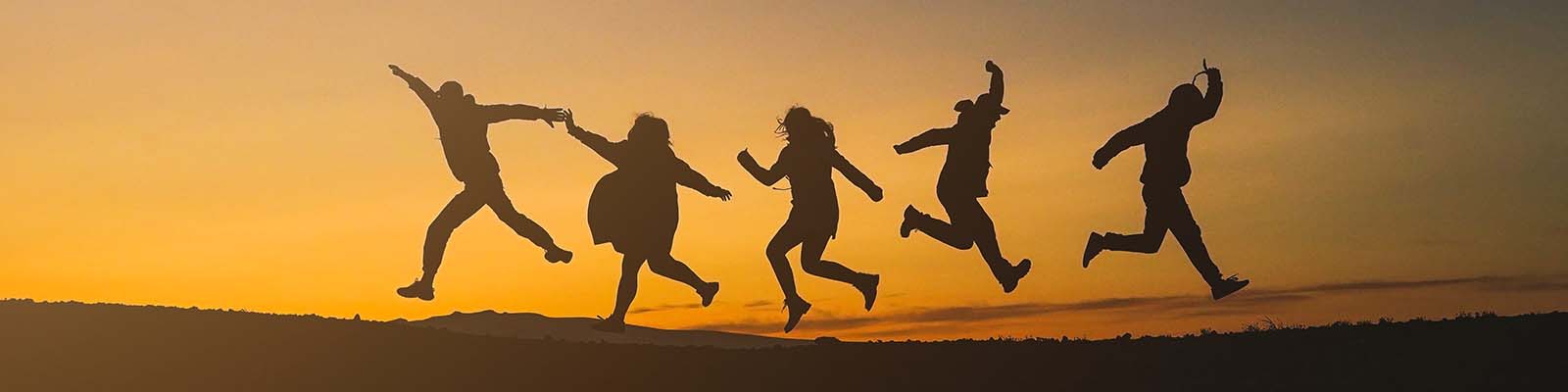 Silhouette of happy people jumping in the sunset